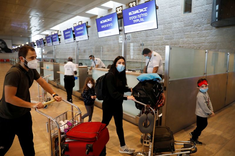 Passengers wearing masks push trolleys at the departures terminal at