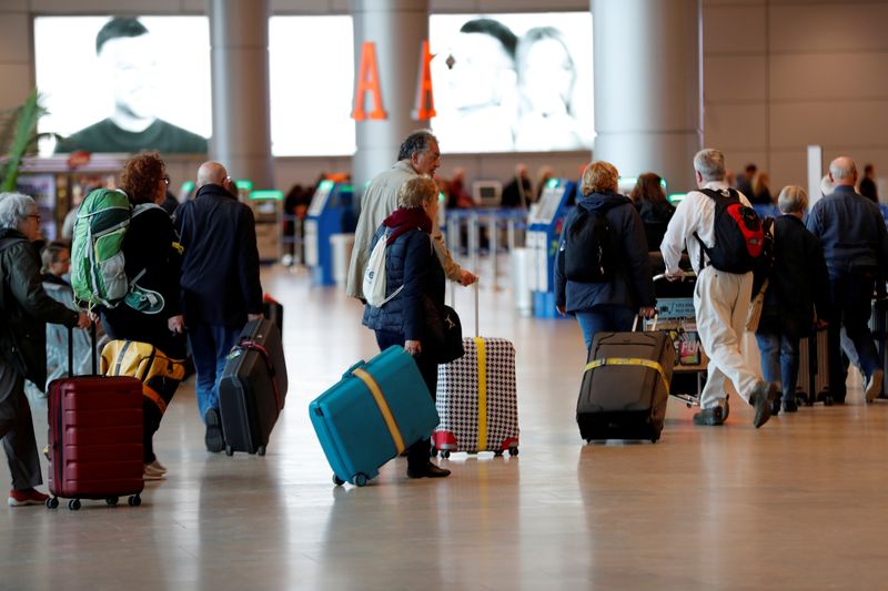 Travelers walk with their suitcases in the departures terminal after