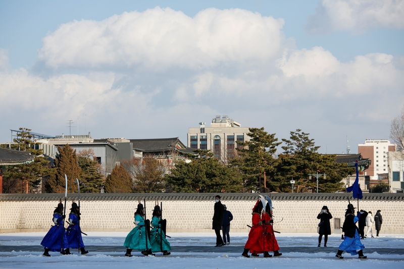 Workers wearing traditional attire walk on a cold winter day,