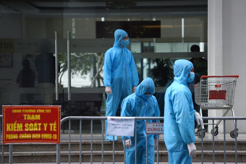 Medical workers in protective suits stand outside a quarantined building