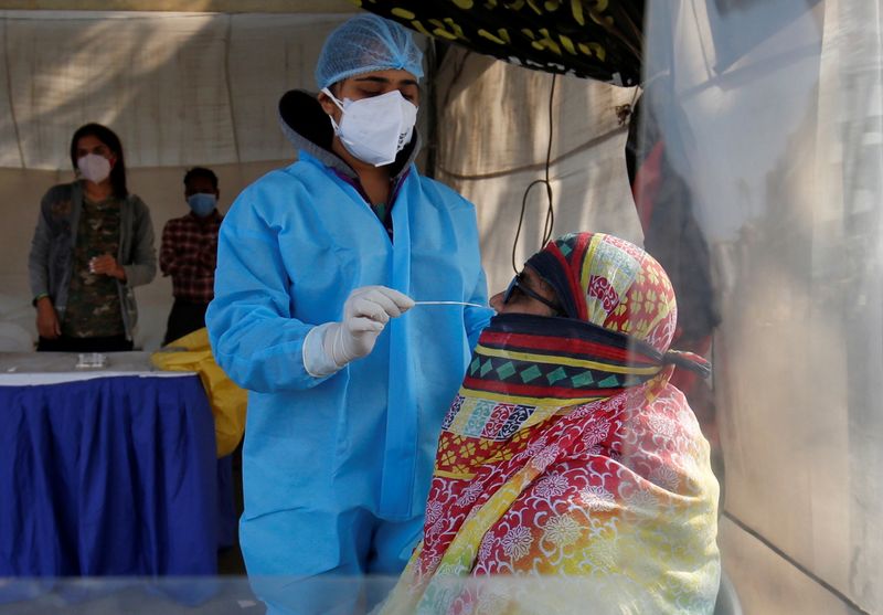 A healthcare worker collects a swab sample from a woman
