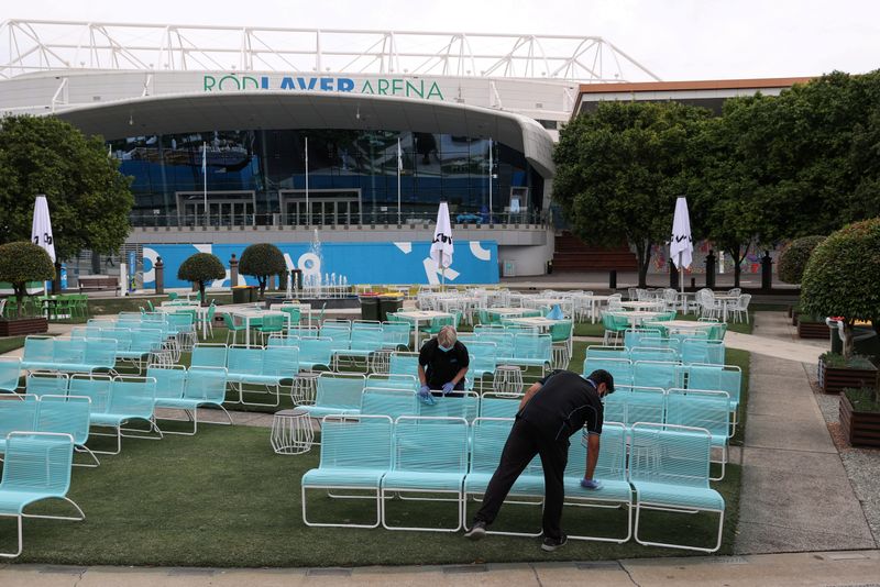 FILE PHOTO: Workers clean a seating area at Melbourne Park