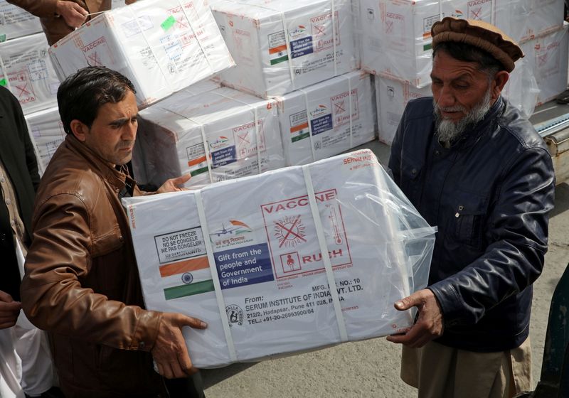 Workers from Afghan health ministry unload boxes containing vials of