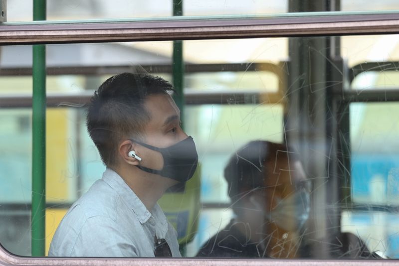 A person wearing a protective face mask rides a tram