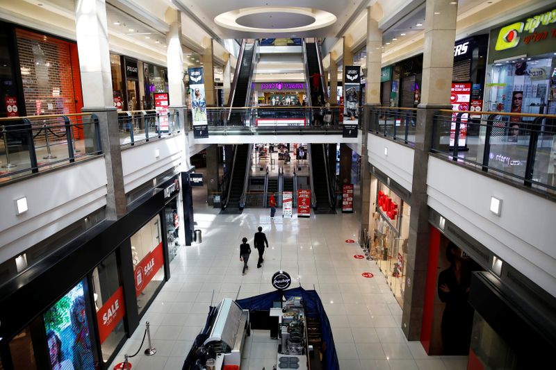 People walk inside a shopping mall with most shops shuttered