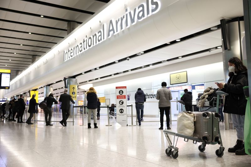 Travellers stand at Terminal 2 of Heathrow Airport, amid the