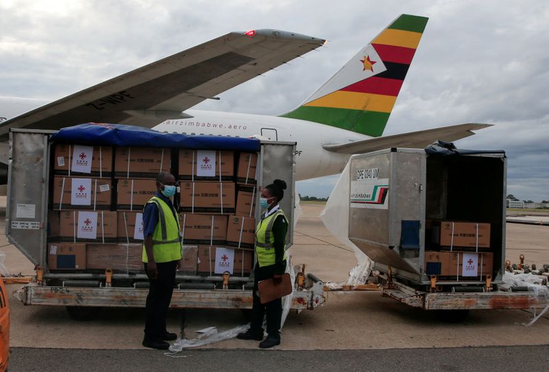 FILE PHOTO: Workers offload boxes as Zimbabwe’s first batch of