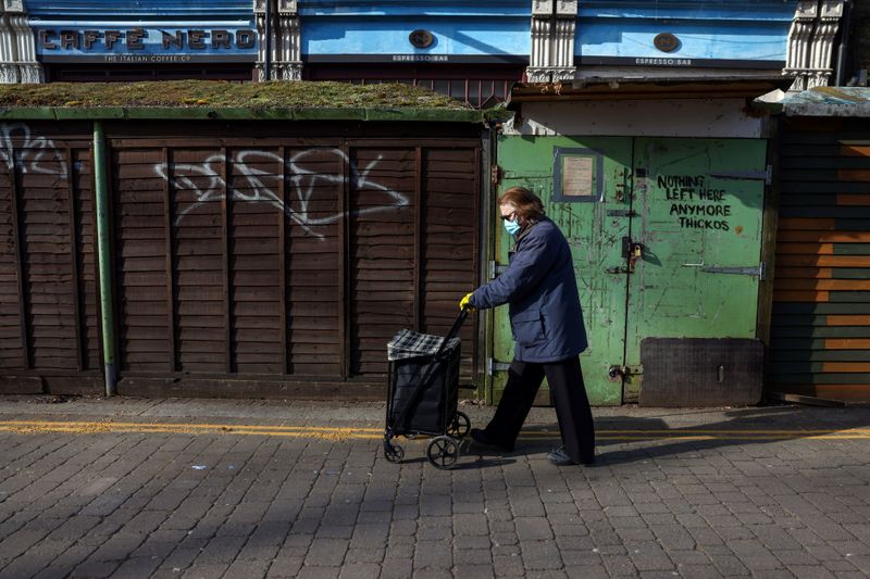 A woman walks past a closed street market in Chiswick