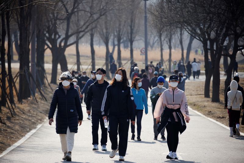 FILE PHOTO: People wearing masks take a walk amid the