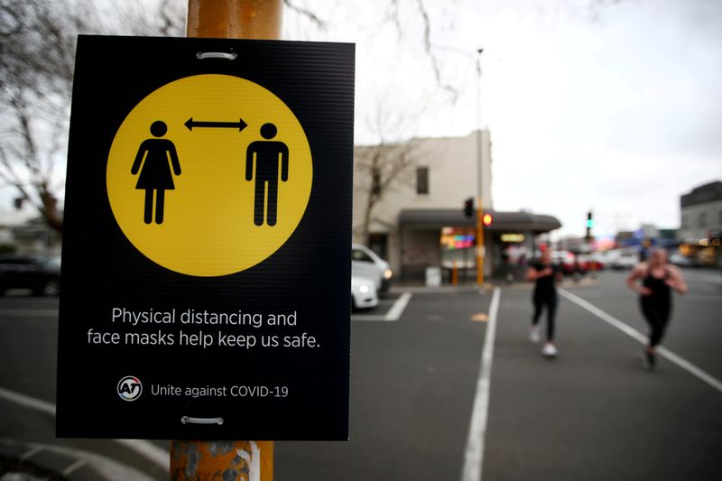FILE PHOTO: People jog past a social distancing sign in