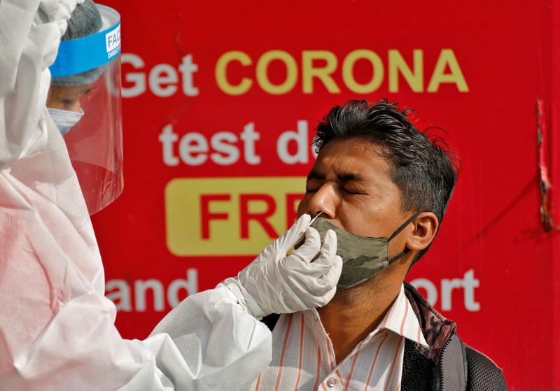 A healthcare worker wearing PPE collects a swab sample from
