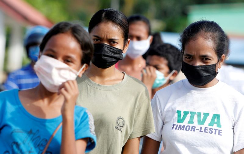 Women wearing protective masks look on as they walk on