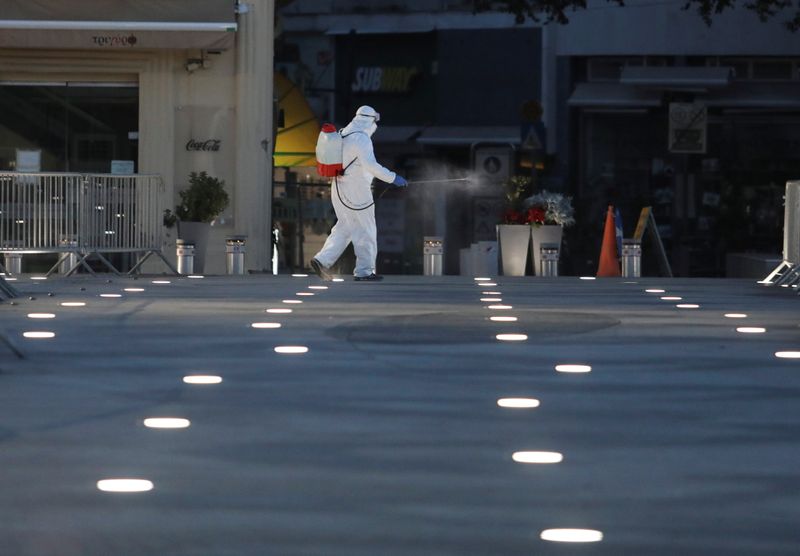 A municipal worker wearing personal protective equipment disinfects Eleftheria square,