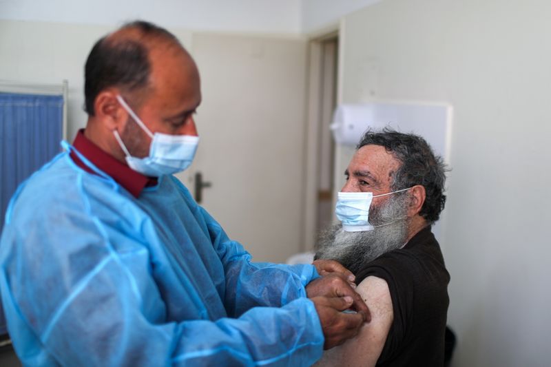 A health worker vaccinates a Palestinian man against the coronavirus