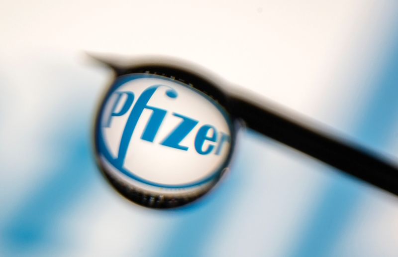 Pfizer logo is reflected in a drop on a syringe