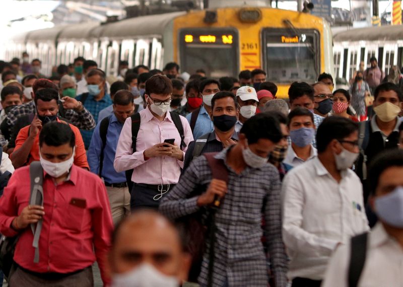 People wearing protective masks walk on a platform at the