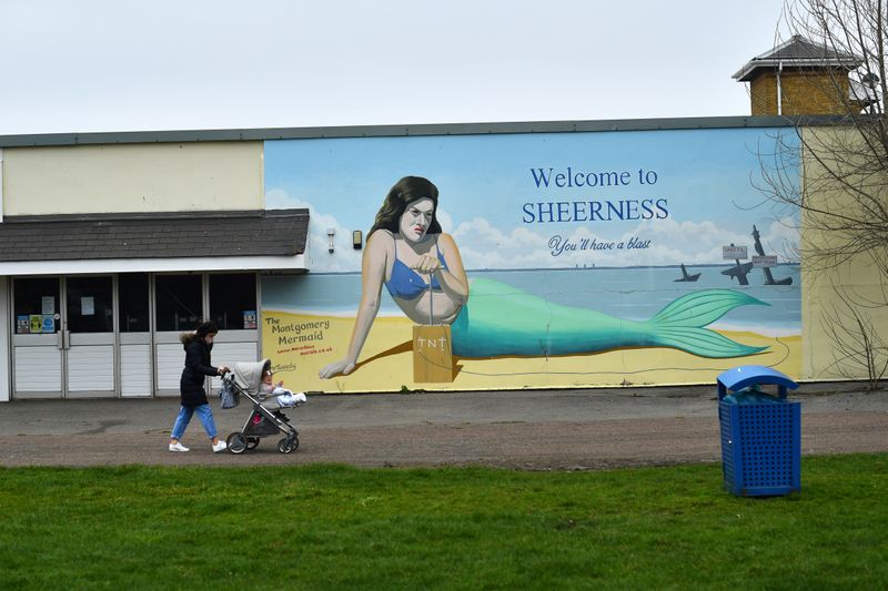 Person walks with a pushchair past a mural of The