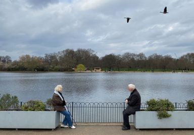 Two people are seen socially-distancing as they chat together in
