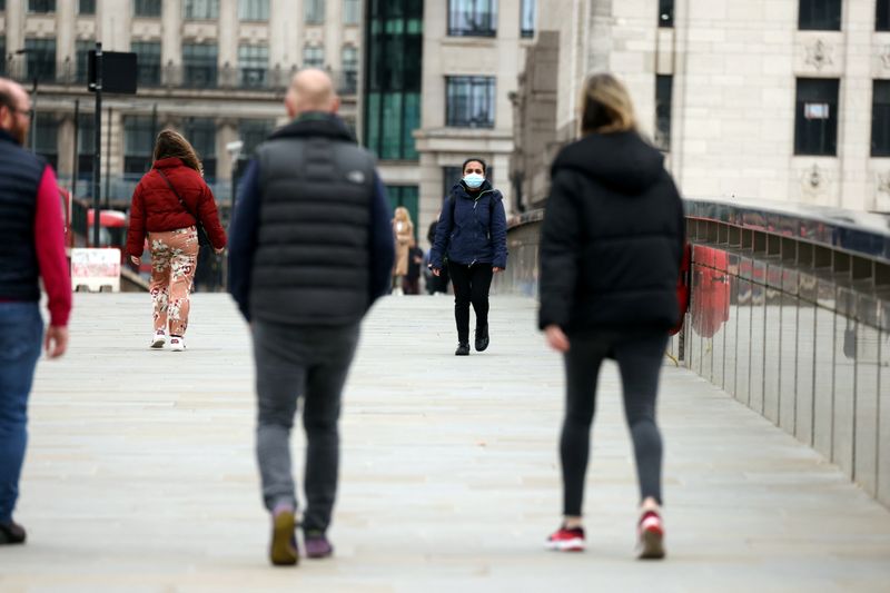 FILE PHOTO: People socially distance as they walk across London