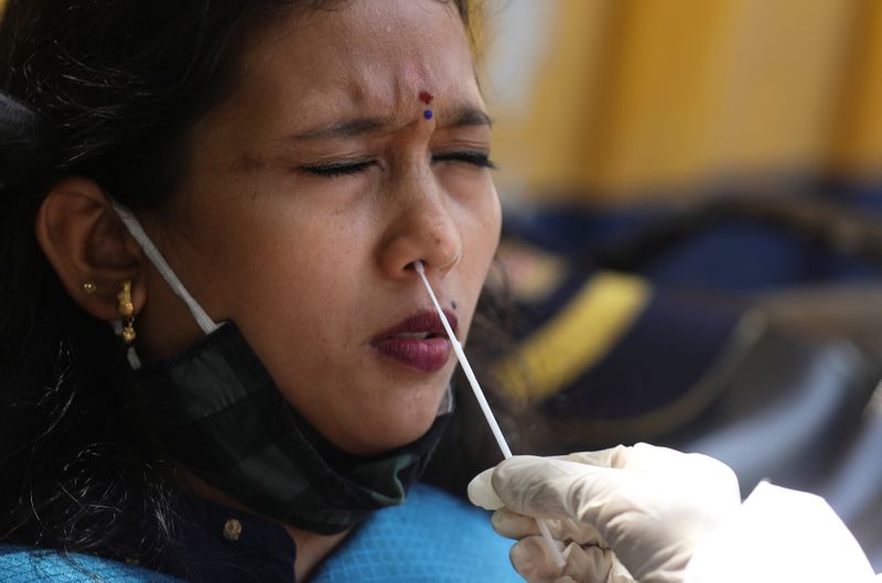 Health worker collects a swab sample from a woman during