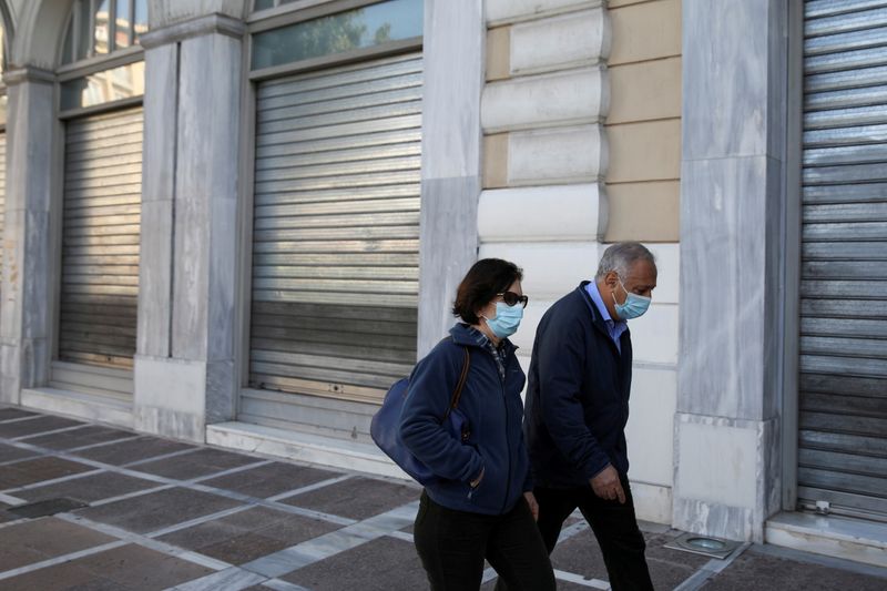 FILE PHOTO: People wearing protective face masks walk past a