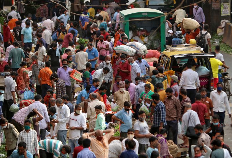 People shop at a crowded marketplace amidst the spread of