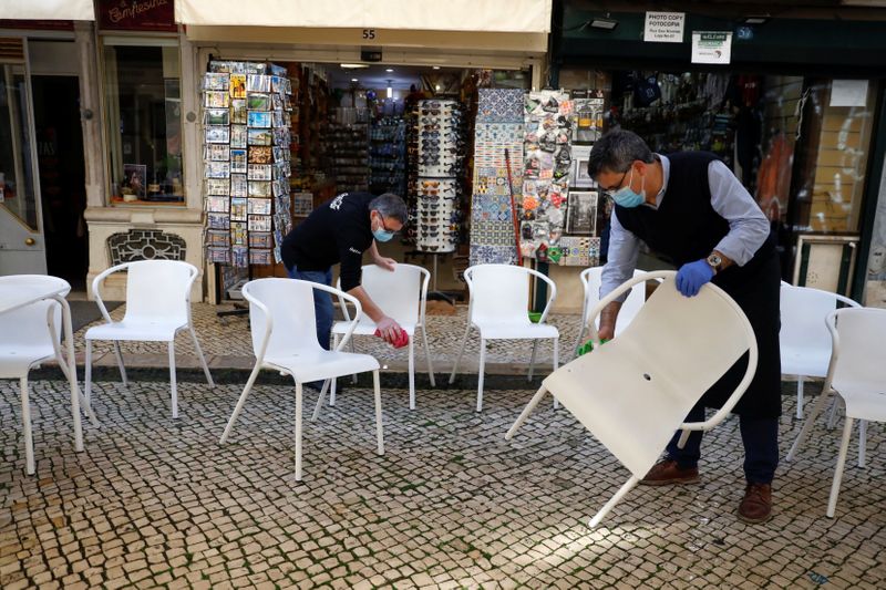 Workers clean chairs to open a restaurant terrace on the