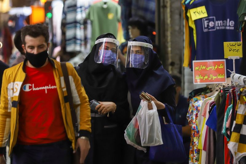 Iranian women wear protective face shields and masks as they