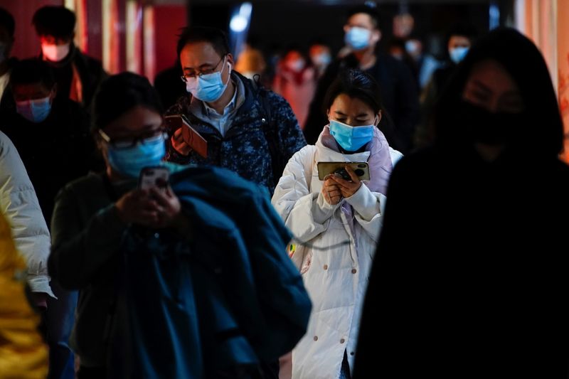 People wearing face masks use their cellphones at a subway