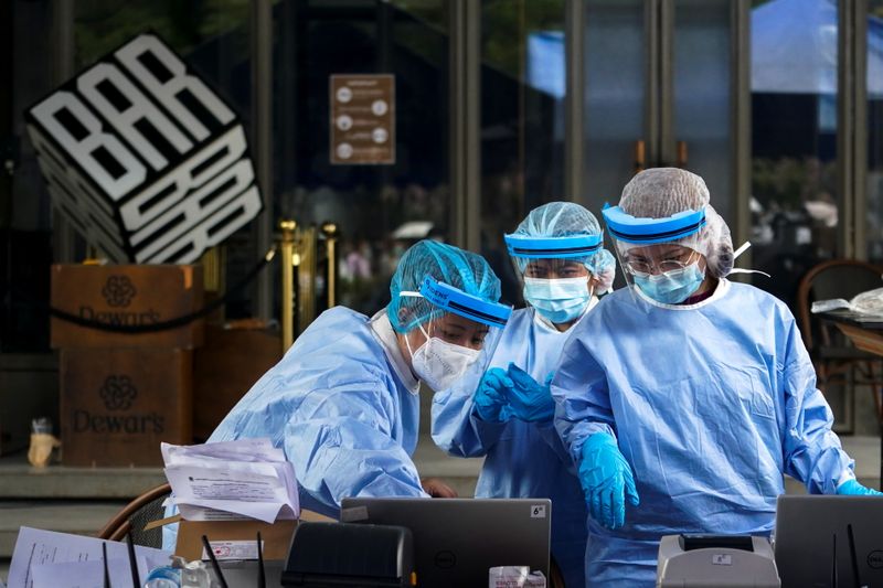 Healthcare workers work in front of a closed bar and