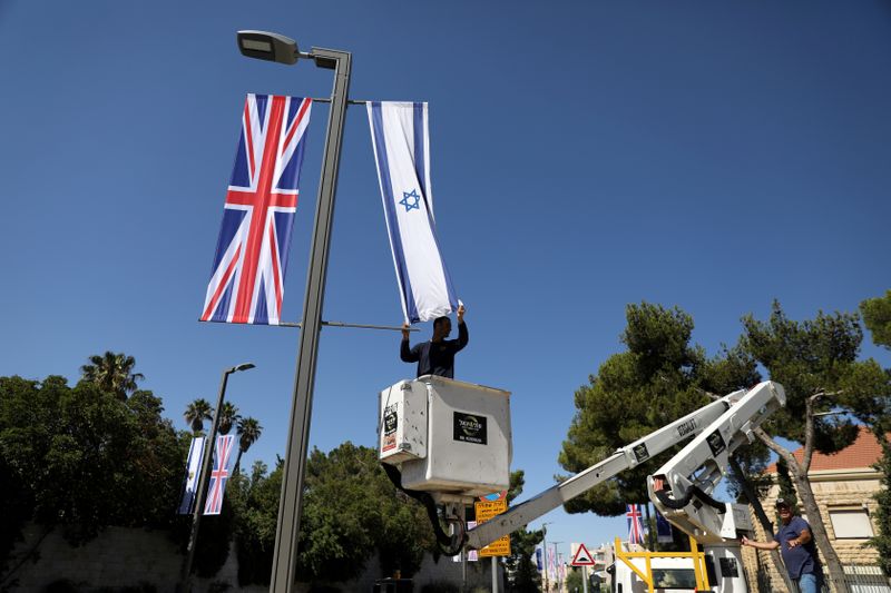 A Jerusalem municipality worker hangs an Israeli flag next to