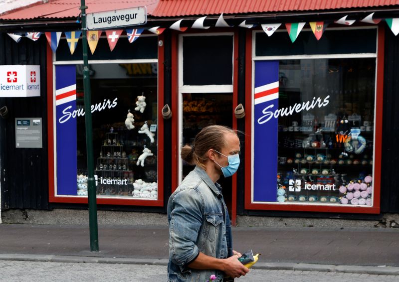 A man with a face mask walks past a tourist