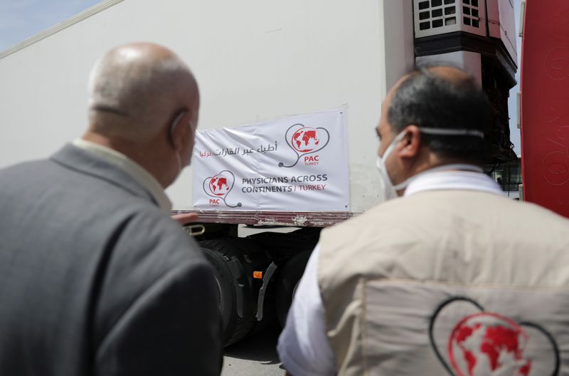 Healthcare workers stand near a truck carrying vaccines against the