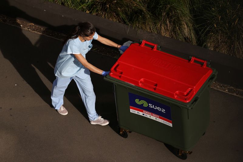 A worker disposes of waste outside a quarantine hotel in