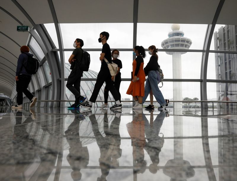 People pass the control tower of Singapore’s Changi Airport