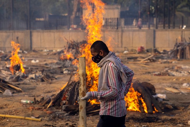 A man walks past burning funeral pyres of people, who