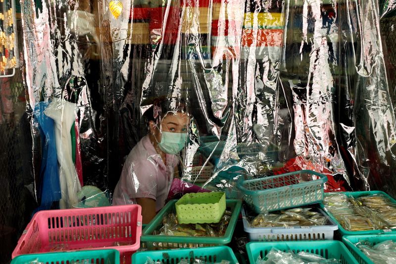 A shopkeeper is seen behind a protecting plastic curtain in