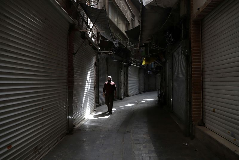 FILE PHOTO: A man walks next to closed shops of