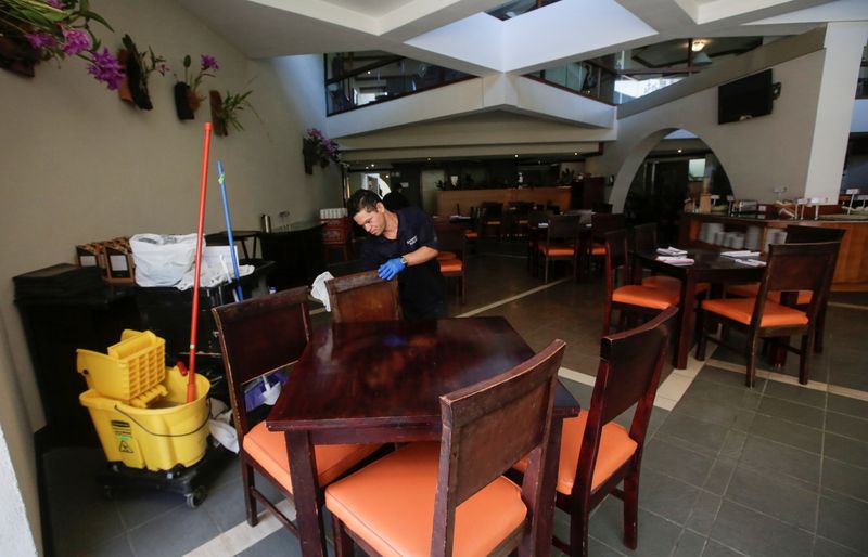 An employee cleans a restaurant chair in a hotel, as