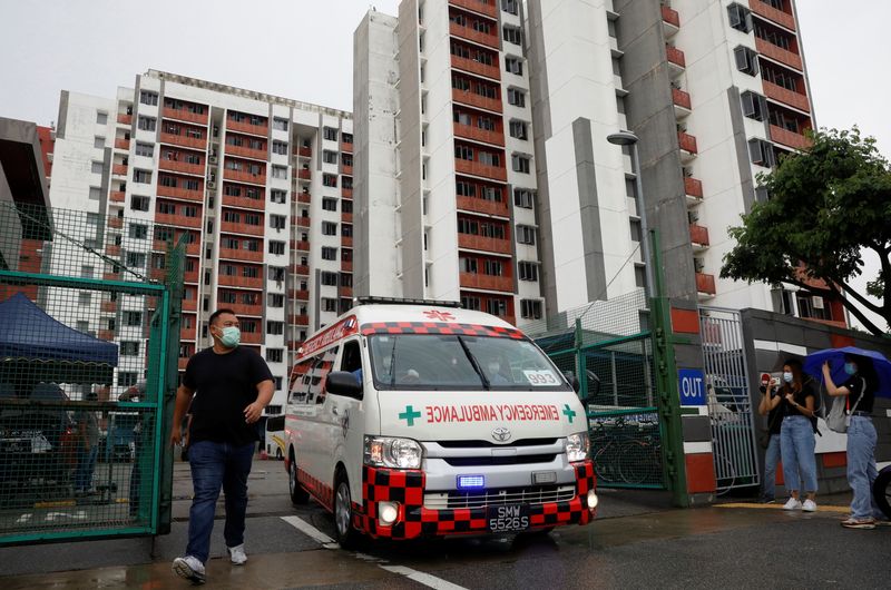 An ambulance carrying a migrant worker leaves Westlite Woodlands dormitory