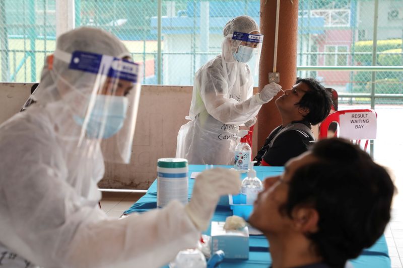 Medical workers collect swab samples from people at a coronavirus