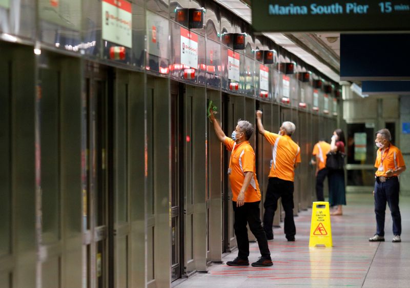 FILE PHOTO: Workers wipe down doors at a train station