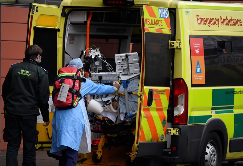 Medical workers move a patient between ambulances outside of the