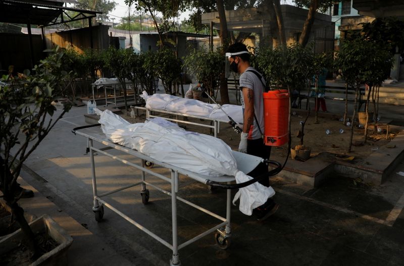 A municipal worker sprays disinfectant on the bodies of victims
