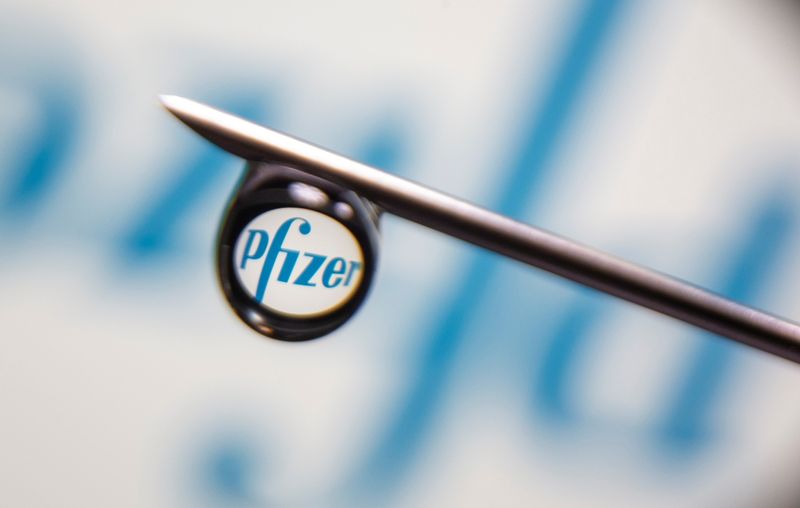 Pfizer logo is reflected in a drop on a syringe