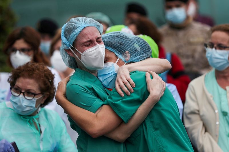 FILE PHOTO: Health workers wearing protective face masks react during