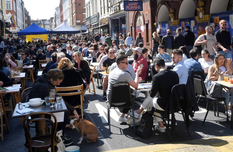 People drink and eat in outdoor street dining areas, as