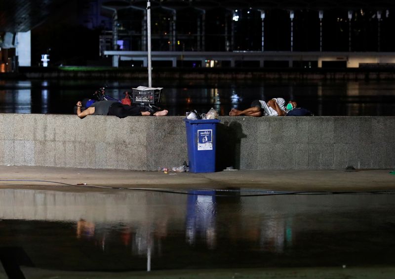 People sleep under a bridge as they wait for a
