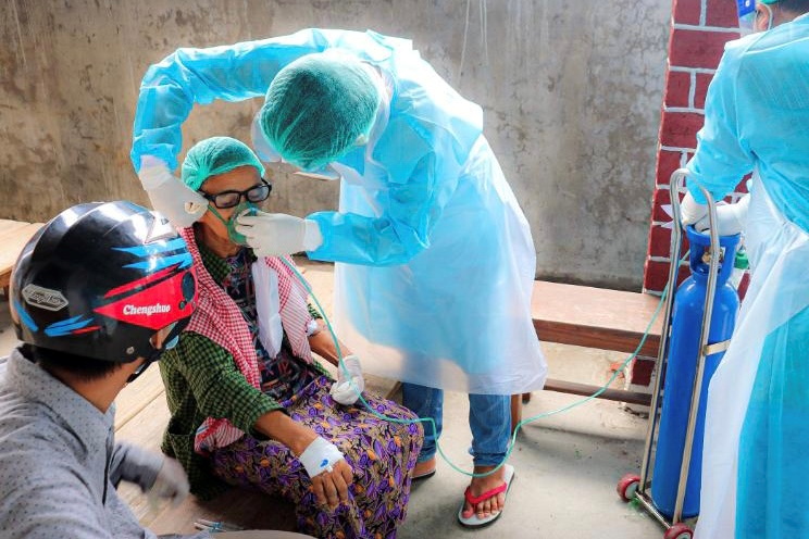 Volunteer adjusts the oxygen mask of a coronavirus disease (COVID-19)