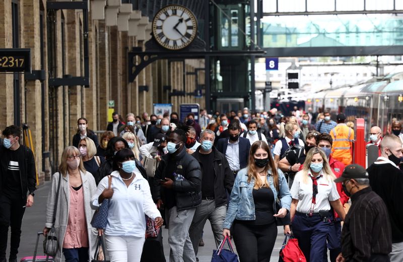 People wearing protective face masks walk along a platform at